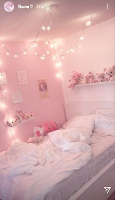 a bedroom with pink walls and lights strung from the ceiling over the bed, along with stuffed animals