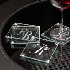 three glass coasters sitting on top of a table with a wine glass in the middle