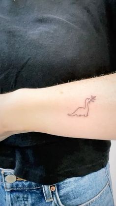 a person with a tattoo on their arm that has a small dinosaur drawn on it