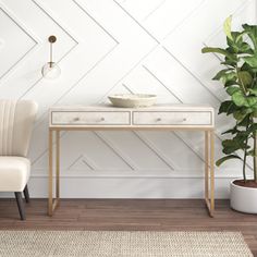 a white table with a bowl on it next to a chair and potted plant