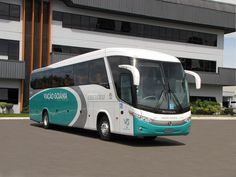 a white and blue bus is parked in front of a large building with two windows