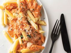 pasta with sauce and parmesan cheese on a white plate next to black utensils