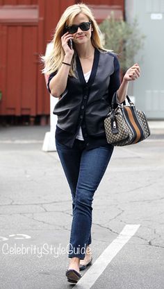 a woman walking down the street talking on her cell phone and holding a purse in her hand