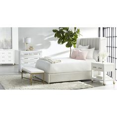 a bedroom with white furniture and a plant in the corner