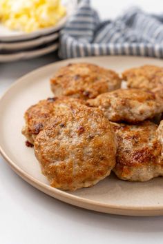 some meat patties are on a plate with macaroni and cheese in the background