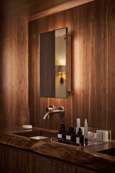 a bathroom sink with soap and lotion on it in front of a wooden wall