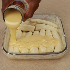 a person pouring sauce on bananas in a container