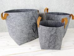 three gray buckets with leather handles sitting on a white table