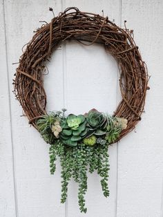 a wreath with succulents and greenery hanging from it