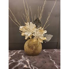 a vase filled with white flowers on top of a table next to a black wall