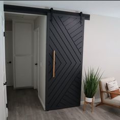 a room with a chair, plant and sliding door that has an arrow design on it