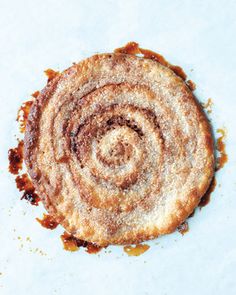 a cinnamon roll is sitting on a white surface with some brown sauce around the edges