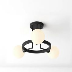 a ceiling light with three white balls hanging from it's center and two black arms