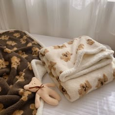 a teddy bear laying on top of a bed next to a brown and white blanket