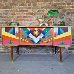 a colorful painted dresser next to a brick wall