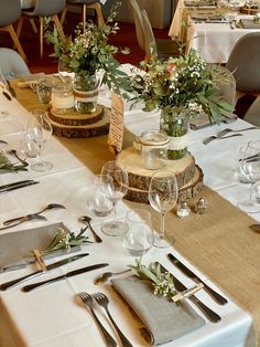 the table is set with silverware and flowers in vases on top of wood slices