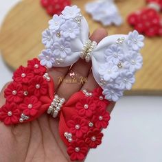 two red and white bows with pearls in the middle are being held by someone's hand