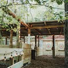 an outdoor target shooting area with trees and lights on the roof, surrounded by woods