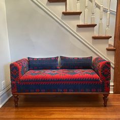 a red and blue couch sitting in front of a stair case