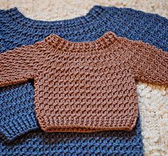 two knitted sweaters sitting on top of carpeted floor next to each other