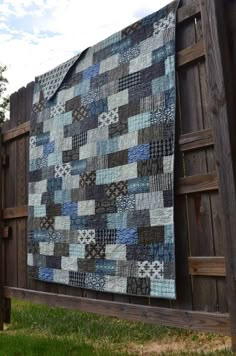 a quilt hanging on the side of a wooden fence