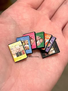 a person's hand holding five small books