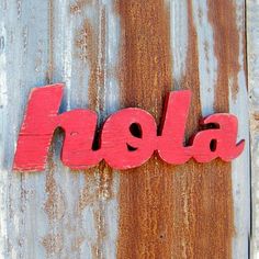 the word hola spelled with red paint on an old rusted metal surface