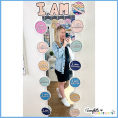 a woman taking a selfie in front of a wall with stickers on it