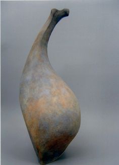 an old vase with a curved neck on a gray background, it appears to be in the shape of a bird