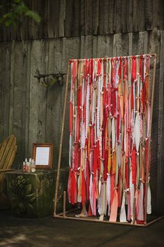 a display with ties hanging from it's sides in front of a wooden fence