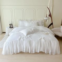 a white bed with ruffled bedspread and pillows