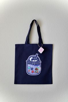 Two of your favorite kinds of Boba's in one? YES! Take the dreamiest boba tote bag with you for all your needs.  __ - Product Description: One (1) Canvas Tote Bag - Color: Dark Navy(Tote Bag), Blue / Brown, Green, Orange, Red (Graphic) - Graphic designed and hand printed with love by Happy Jensday - Slight variations per item may occur due to its handmade nature Fun Handmade Bags For Daily Use, Novelty Multicolor Bag For Everyday Use, Fun Handmade Bags For Everyday Use, Handmade Fun Bags For Everyday Use, Kawaii Rectangular Canvas Bag Gift, Kawaii Tote Bag For Gift, Fun Rectangular Bags For Gifts, Kawaii Multicolor Shoulder Bag As Gift, Fun Rectangular Bags Ideal For Gifts