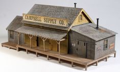 a model train station with a small building on the platform and a sign that says campbell supply co