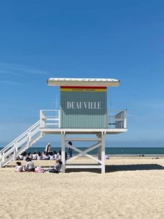 people are sitting on the beach under a lifeguard's hut at deavillee