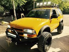 a yellow pick up truck parked on top of a sidewalk