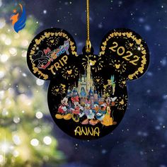 a mickey mouse ornament hanging from a christmas tree with disney world in the background