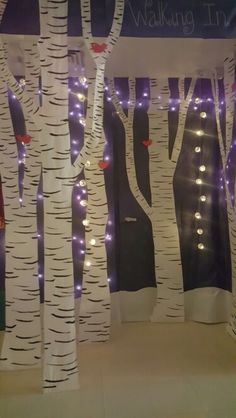 the display is decorated with white birch trees and purple lights in front of it,