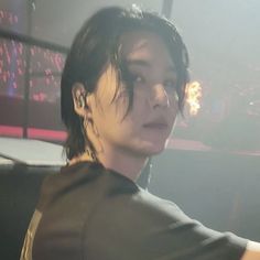 a man with black hair and piercings standing in front of a stage