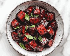 a white bowl filled with cooked food on top of a marble countertop next to a spoon