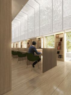 a man sitting at a desk in a room with bookshelves on the walls