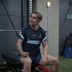 a man sitting on top of a bench in a gym