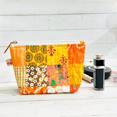 an orange and yellow patchwork purse next to a camera