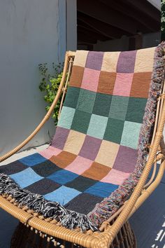 a woven blanket sitting on top of a wicker chair