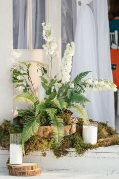 white flowers and greenery sit in front of a window