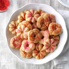 a white bowl filled with sugary donuts on top of a table