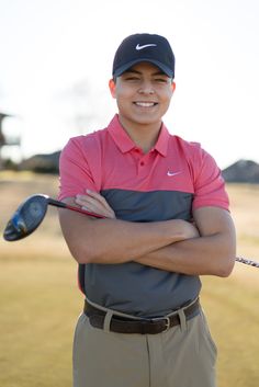 a man standing with his arms crossed in front of him and holding a golf club