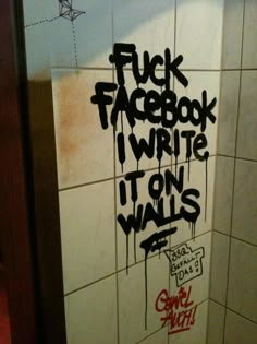 graffiti is spray painted on the wall of a bathroom stall in an area with white tiles