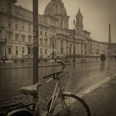 a bike parked on the side of a street next to a building with a clock tower