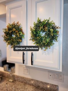 two wreaths are hanging on the cabinets