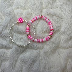 two bracelets with pink and white beads are laying on a furnishing surface